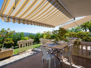 une terrasse avec une table et des chaises sous un parasol dans l'établissement Apartment Primula - VLO206 by Interhome, à Lecchiore