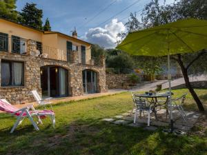 una mesa, sillas y una sombrilla frente a una casa en Apartment Joy - IMP521 by Interhome, en Imperia