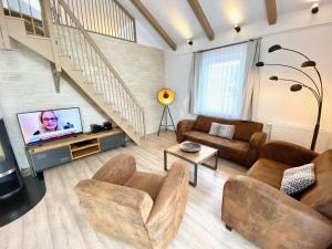 a living room with couches and a tv and stairs at mönchgut living & spa in Gager