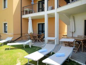 a patio with chairs and tables and umbrellas at Apartment Belvedere Village-2 by Interhome in Cavalcaselle
