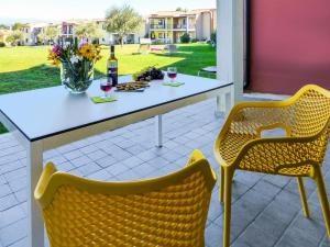 a table with a bottle of wine and two chairs at Apartment Belvedere Village-2 by Interhome in Cavalcaselle