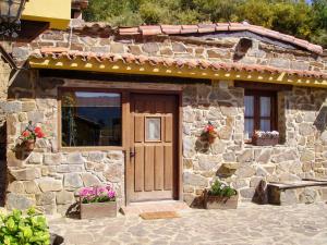 una casa de piedra con una puerta de madera y flores en Apartment Potes Vinon - Cabaña by Interhome, en Tama