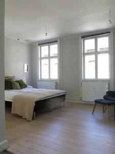 um quarto com uma cama grande e 2 janelas em ApartmentInCopenhagen Apartment 1143 em Copenhague