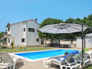 a pool with chairs and an umbrella and a house at Apartment Radmila-1 by Interhome in Gostinjac