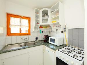 バラトンマーリアフュルドゥーにあるHoliday Home Maria by Interhomeの白いキャビネット、シンク、電子レンジ付きのキッチンが備わります。