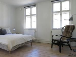 a bedroom with a bed and a chair and windows at ApartmentInCopenhagen Apartment 1144 in Copenhagen