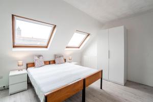 een slaapkamer met een groot bed en 2 ramen bij Sunny Spacious Apartment De Bijenkorf in Zandvoort