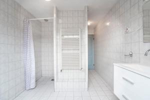 een witte badkamer met een douche en een wastafel bij Sunny Spacious Apartment De Bijenkorf in Zandvoort