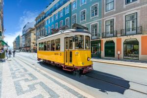 a yellow tram driving down a city street at Life is Good in Lisbon Baixa in Lisbon