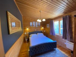 um quarto com uma cama azul num quarto de madeira em Owlet Lodge at Owlet Hideaway - with Hot Tub, Near York em Seaton Ross