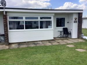 a garage with a table and a chair in a yard at 125 Sundowner in Hemsby