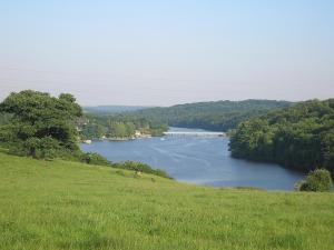a view of a river with a bridge in the distance at Glamping des 2 Marguerites in Bazoches-au-Houlme
