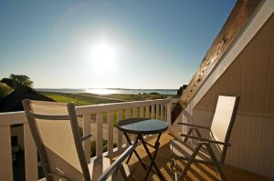two chairs and a table on a balcony with the ocean at mönchgut living & spa in Gager