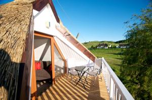 a balcony of a thatch hut with a table and chairs at mönchgut living & spa in Gager