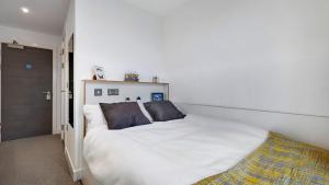 a bedroom with a large white bed with two pillows at Zeni Ensuite, in Colchester in Colchester