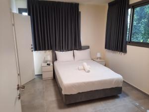 a bedroom with a bed with white sheets and a window at Dizengoff Inn Apartments in Tel Aviv