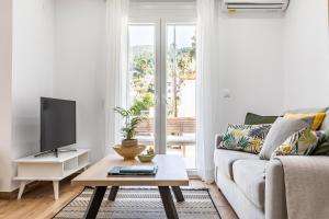 een woonkamer met een bank en een tv bij Sea Senses Apartment in Skopelos Town