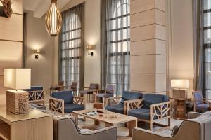 a lobby with blue chairs and tables and windows at Atlantica Aeneas Resort in Ayia Napa