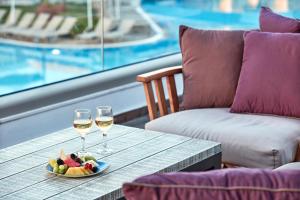 a table with two glasses of wine and a plate of fruit at Atlantica Aeneas Resort in Ayia Napa