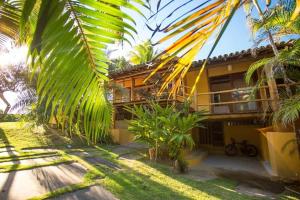 a building with palm trees in front of it at Bangalo Outeiro das Brisas in Praia do Espelho