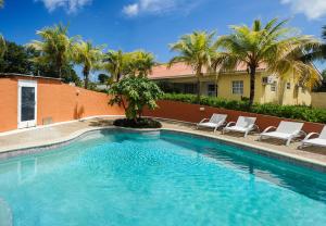 een groot zwembad met stoelen en palmbomen bij ABC Resort Curacao in Willemstad