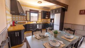 a kitchen with a table with chairs and a kitchen with black cabinets at Casa Rural Silvia y Melissa in La Puebla de Cazalla