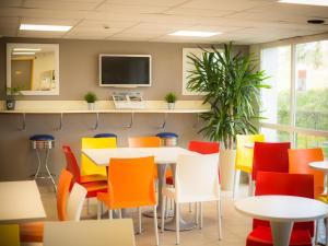 a dining room with colorful chairs and tables at Premiere Classe Lisieux in Lisieux