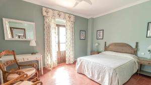 ein Schlafzimmer mit einem Bett und einem Stuhl und einem Fenster in der Unterkunft Hacienda El Corchuelo in Marchena