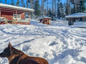 a dog standing in the snow in front of a cabin at Holiday Home Juurlahti by Interhome in Hara
