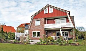 uma casa de tijolos vermelhos com um telhado vermelho em Pension Leuchtfeuer em Norden