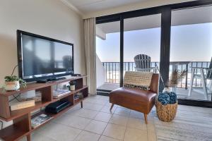 a living room with a flat screen tv and a chair at Island Winds East in Gulf Shores