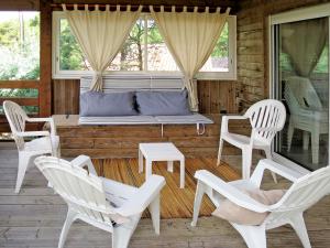 a porch with white chairs and a bench on a porch at Chalet La Cigale - MAU190 by Interhome in Carcans