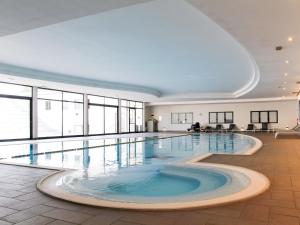 a large swimming pool in a large building with windows at Apartment Eden by Interhome in Cavalcaselle