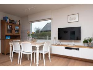 a dining room with a table and chairs and a tv at Quiet location yet close to the beach and center large enclosed garden in Renesse