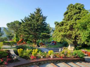 un parc avec un jardin planté de fleurs et d'arbres dans l'établissement Holiday Home Mobilhome B - AEG402 by Interhome, à Villanova dʼAlbenga