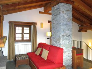 um sofá vermelho numa sala de estar com um pilar de pedra em Chalet Casot Pra Viei - SMY100 by Interhome em Sampeire