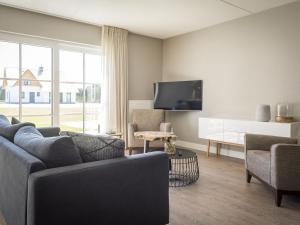 a living room with a couch and chairs and a tv at Apartment in tasteful farmhouse in De Cocksdorp in De Cocksdorp