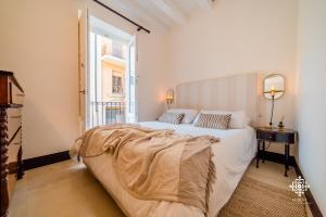een witte slaapkamer met een groot bed en een raam bij Casa Ramal - Tipica dimora Siciliana in Siracusa