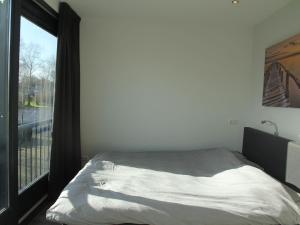 - une chambre avec un lit et une grande fenêtre dans l'établissement Charming Apartment in Langweer with Jetty, à Langweer