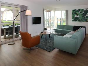 sala de estar con sofá y TV en Thatched villa with lounge set, right at the water, en Delfstrahuizen