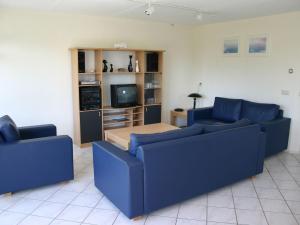 sala de estar con 2 sofás azules y TV en Comfy bungalow with a dishwasher, at the water en Medemblik