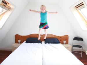 HippolytushoefにあるComfortable villa on a holiday park in Wieringer style, near the Wadden Seaの少女がベッドの上に飛び乗る