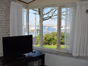 ein Wohnzimmer mit einem Flachbild-TV und einem Fenster in der Unterkunft Detached holiday home with sauna in Kamperland