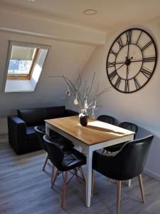 a dining room with a table and a large clock at Apartamentai Ramybė in Nida