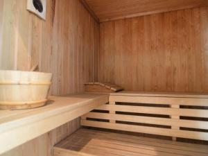 uma sauna de madeira com prateleiras de madeira e um balde em Holiday home with pool sauna em Lunteren