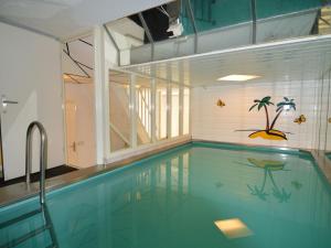 a swimming pool in a house with a palm tree on the wall at Holiday home with pool sauna in Lunteren