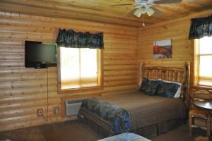 a bedroom with a bed and a flat screen tv at Bryce Country Cabins in Tropic
