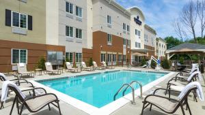 a pool at a hotel with chairs and a hotel at Candlewood Suites Grove City - Outlet Center, an IHG Hotel in Grove City