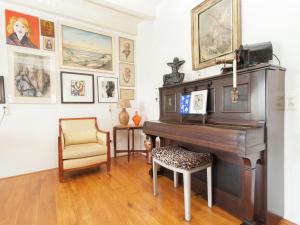 スコールルにあるHoliday home in Schoorl with a gardenのピアノと椅子、絵画が備わる部屋