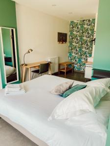 een groot wit bed in een kamer met een bureau bij Le Clos Vernay in Nivolas-Vermelle